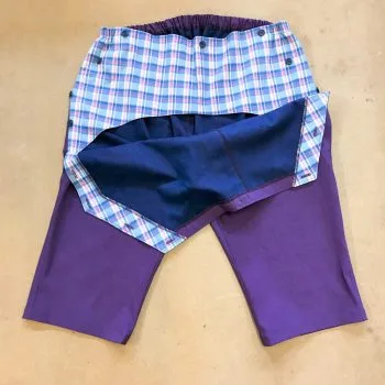 Purple shorts showing front flap open to reveal inner lining which is blue checked